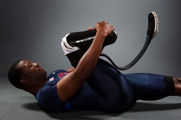 image of a black man with a prosthetic leg, lying on his back and stretching