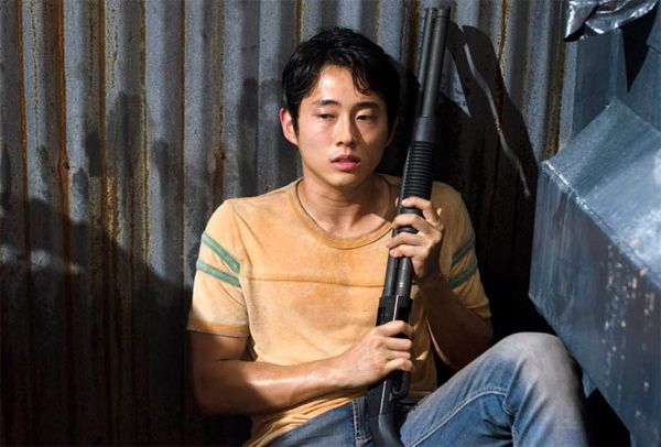 image of Glenn sitting in an alley behind a dumpster with a shotgun looking pensive and scared