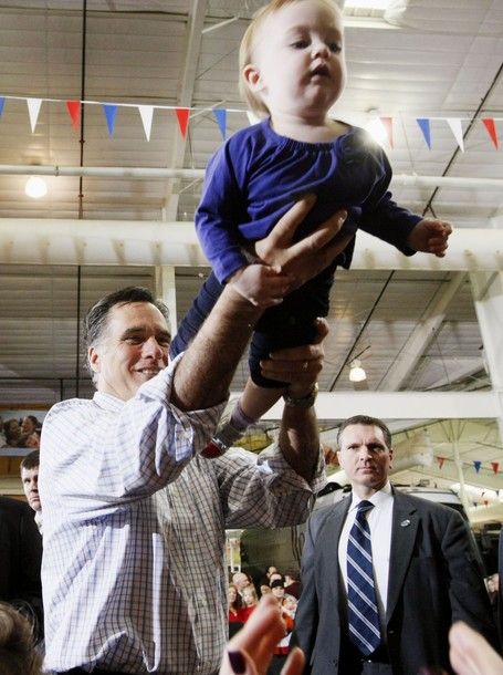 Mitt Romney holds a baby in the air at a campaign event