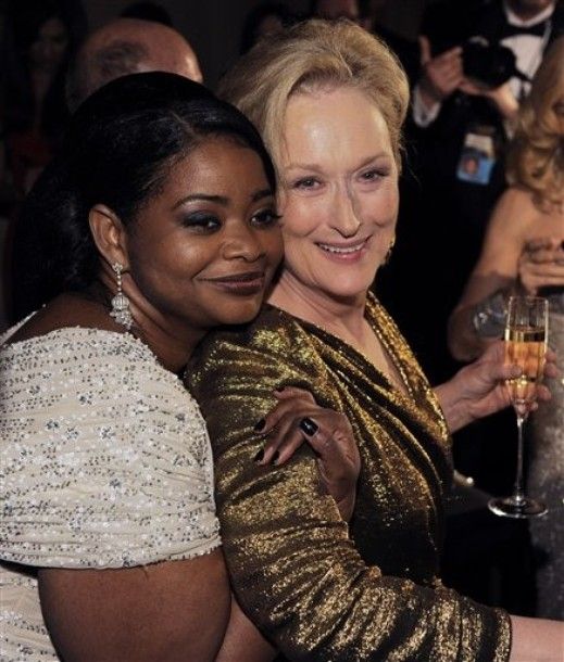 image of Oscar winner Octavia Spencer hugging Oscar winner Meryl Streep from behind; Streep is leaning into her and holding a glass of champagne
