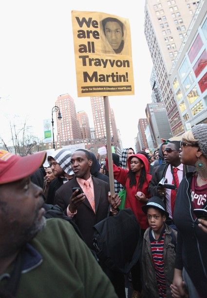 image of a group of protestors, one of whom, a black man, is holding a sign with an image of Trayvon Martin, reading 'We Are All Trayvon Martin'