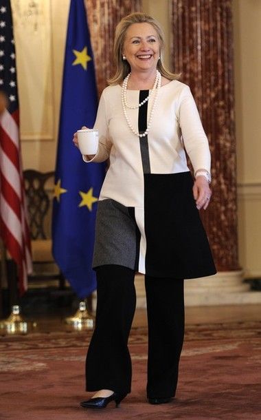 image of Hillary Clinton walking and grinning, while holding a coffee cup