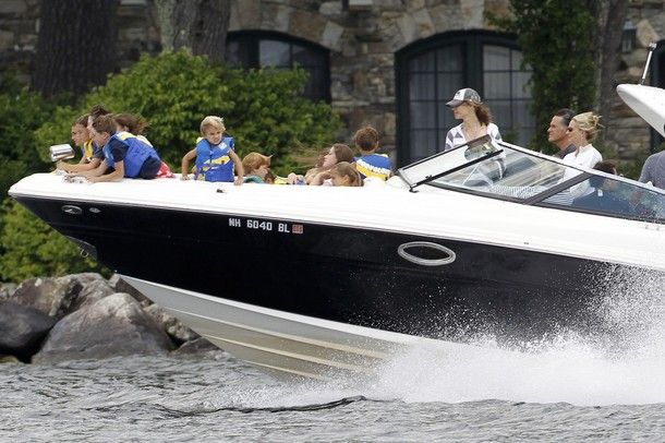 image of Mitt and Ann Romney speeding in their boat with about a dozen kids in the bow