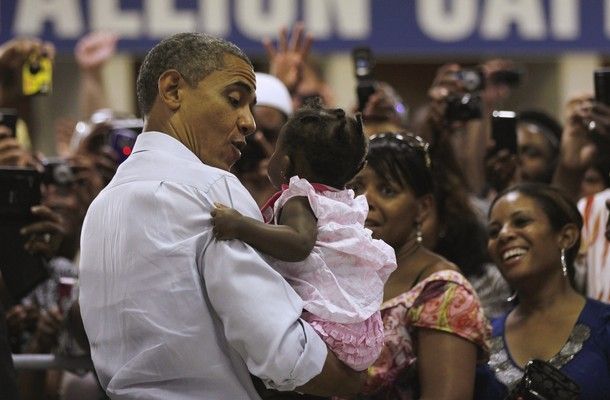 image of President Barack Obama at a campaign event, holding a black baby girl in a pink dress