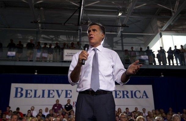 image of Mitt Romney at a campaign event, standing in front of a sign reading 'Believe in America,' part of which he's blocking out so it looks like it says 'Believe Erica.'