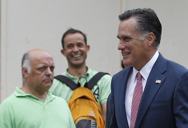 image of Mitt Romney on a street corner in London, with one older male pedestrian who appears to be white scowling mightily at him and another younger male pedestrian who appears to be white laughing at him