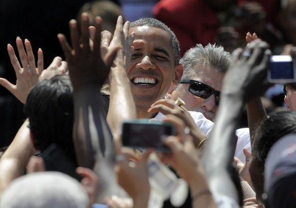 image of President Barack Obama at a campaign appearance, smiling as a crowd of people lift their arms toward him