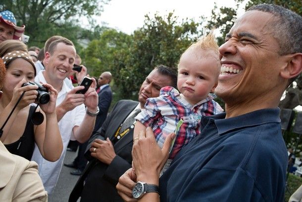 image of President Barack Obama laughing while holding a white baby with a mohawk who is making a funny face