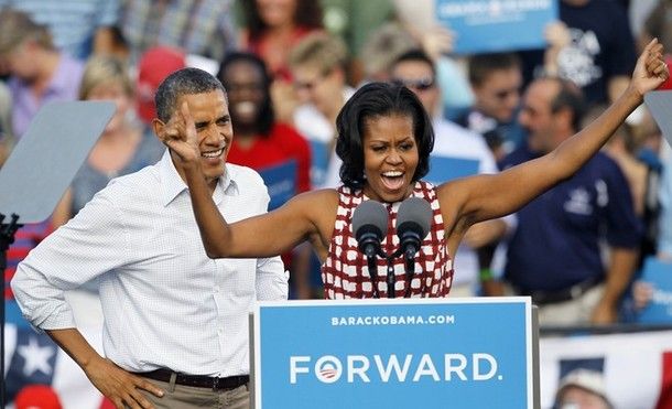 image of First Lady Michelle Obama at a podium, triumphantly lifting her arms, while President Barack Obama gazes on proudly
