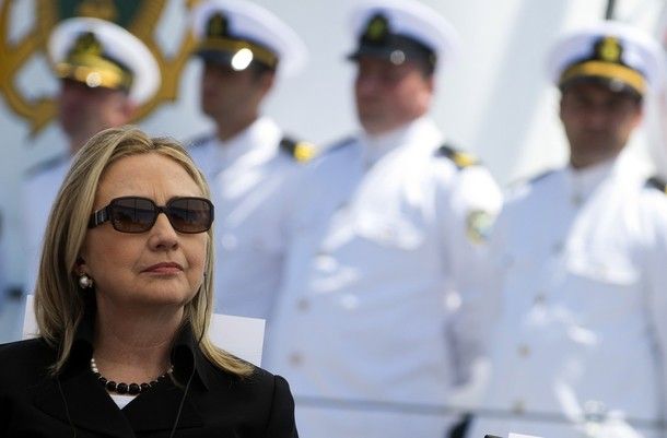 image of Hillary Clinton, wearing shades while standing near members of the Coast Guard in their whites