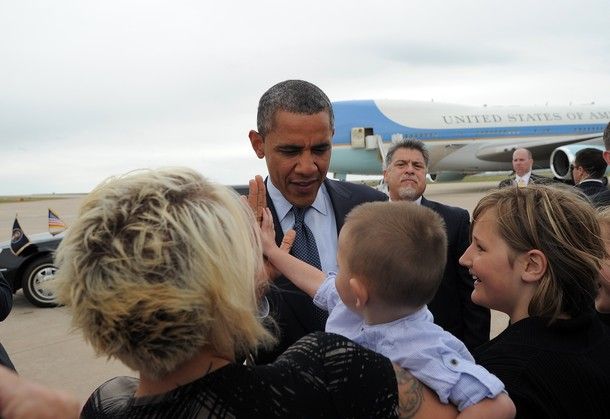 President Barack Obama high-fives a little white boy being held in (presumably) his mother's arms