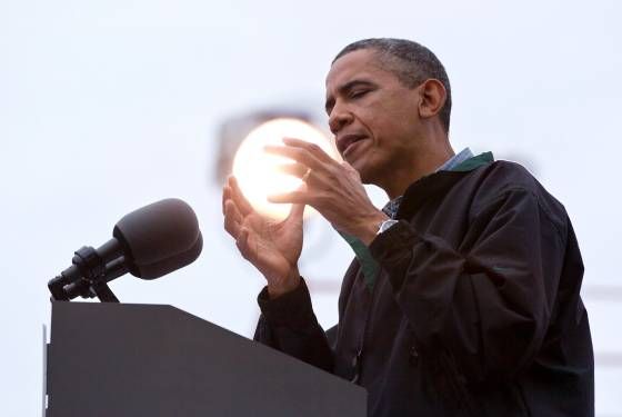 image of President Obama at a podium during a campaign event, holding his hands up in a way that looks like he's gripping the sun behind him as if it's a palantir