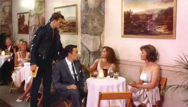 image of Patrick Swayze and Jennifer Grey from Dirty Dancing, in which Grey is sitting with her onscreen parents and Swayze is imploring her to come dance with him.
