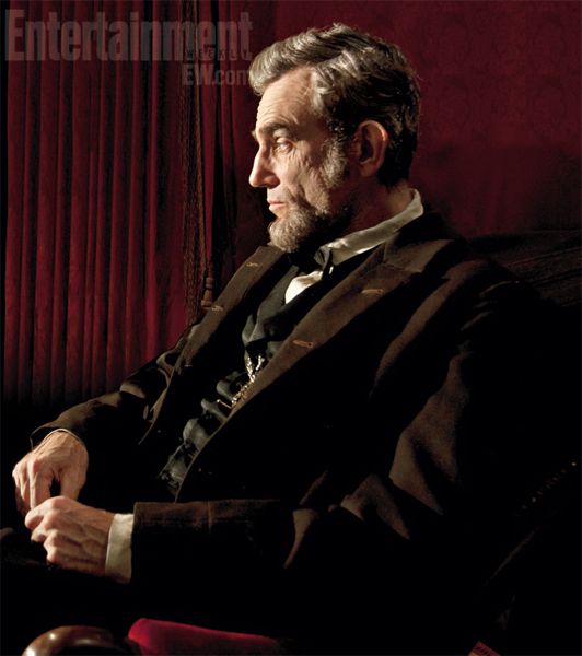 image of actor Daniel Day-Lewis in costume as Abraham Lincoln, sitting in profile in front of a red curtain