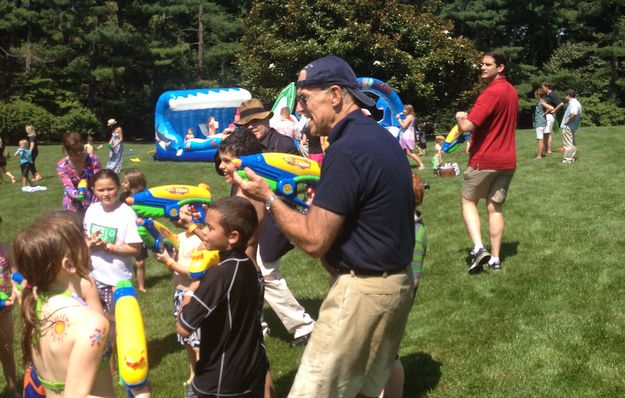Vice President Joe Biden holding a water gun, while soaking wet and surrounded by kids who are also holding water guns