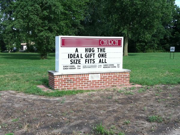 image of a church sign reading: 'A HUG THE IDEAL GIFT ONE SIZE FITS ALL'