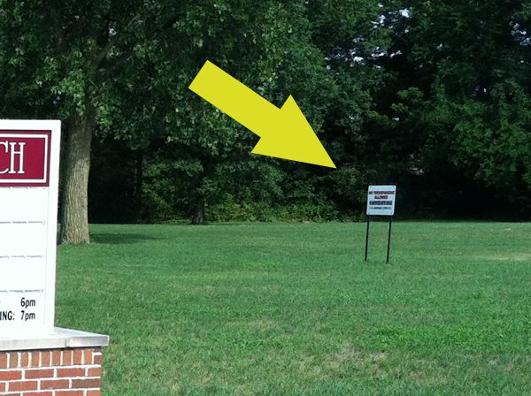 section of previous image with yellow arrow added to point to 'No Trespassing' sign on church grounds