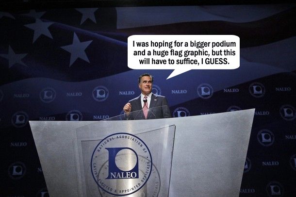 Mitt Romney stands at a ginormous silver podium with a huge flag graphic behind him; I have added a dialogue bubble reading: 'I was hoping for a bigger podium and a huge flag graphic, but this will have to suffice, I GUESS.'