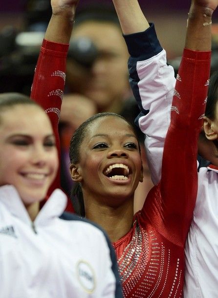 US Olympic gymnast Gabrielle Douglas lifts her arms in the air in celebration after the women's team took gold