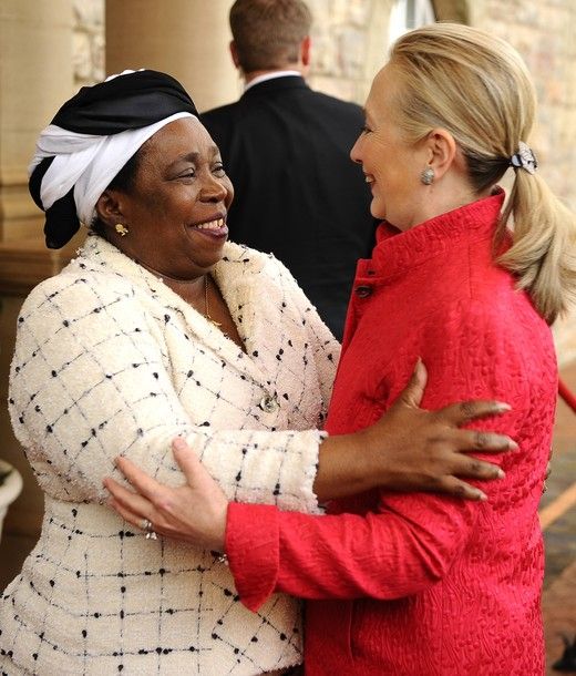 image of Secretary of State Hillary Clinton, a white woman, embracing chairperson of the African Union Commission Nkosazana Dlamini-Zuma, a black woman; they are holding each other and smiling at one another