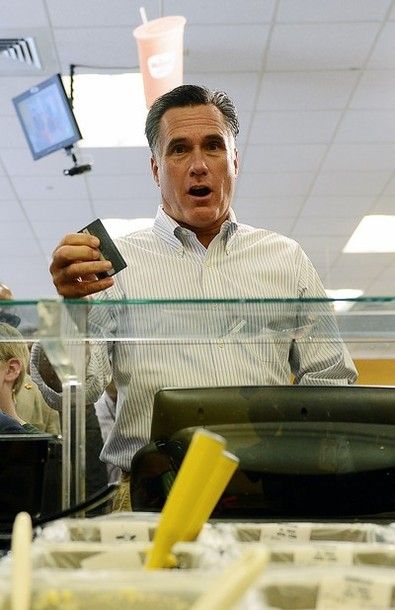 image of Mitt Romney holding a credit card with a surprised look at a sandwich counter in a gas station