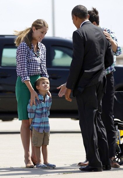 image of President Obama standing across a little white boy, who is standing in front of his white mother, sort of leaning back against her legs, looking up at the President; his white father is standing beside the President with his hand on the President's shoulder
