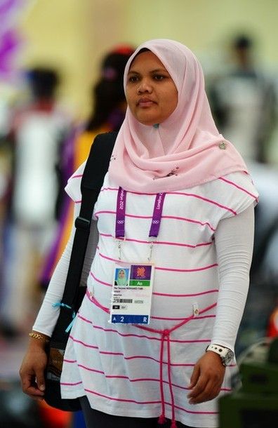 image of a very pregnant Nur Suryani Mohamed Taibi, a Malaysian woman in a pink headscarf carrying her rifle bag