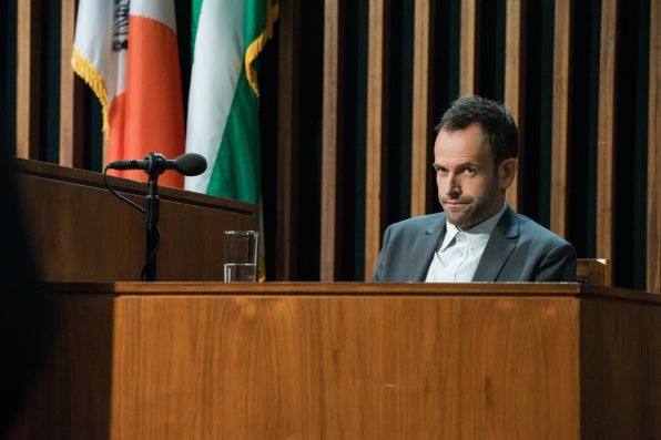 image of Jonny Lee Miller as Sherlock Holmes, pictured on the stand in a courtroom, scowling
