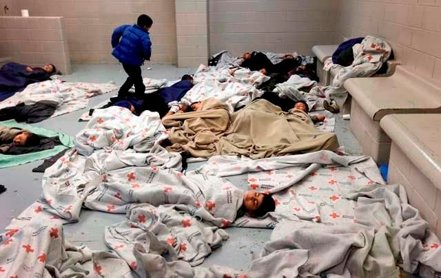 image of lots of children with blankets sleeping higgledy-piggledy on a cement floor