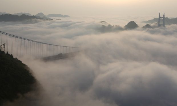 image of a suspension bridge shrouded in fluffy clouds on a misty morning