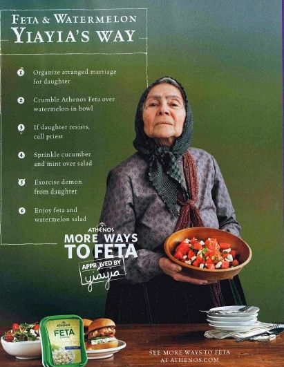 picture of an older woman wearing a scarf on her head and holding a wood bowl full of feta and watermelon salad, who is meant to be Yiayia, accompanied by text reading: 'Feta & Watermelon Yiayia's Way: 1. Organize arranged marriage for daughter. 2. Crumble Athenos Feta over watermelon in bowl. 3. If daughter resists, call priest. 4. Sprinkle cucumber and mint over salad. 5. Exorcise demon from daughter. 6. Enjoy feta and watermelon salad.'