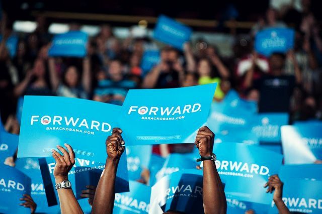 image of hands raised holding 'Forward' signs at an Obama campaign event