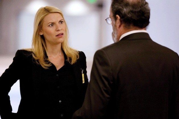 image of Carrie (Claire Danes) standing in a hallway talking to Saul (Mandy Patinkin)