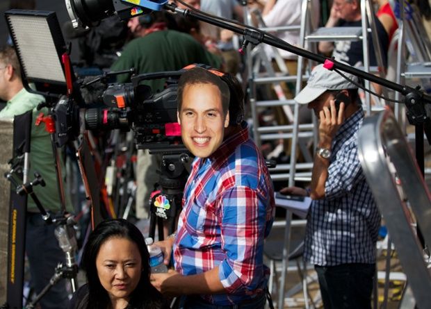 image of a cameraman wearing a Prince William mask on the side of his head in the middle of a press gaggle