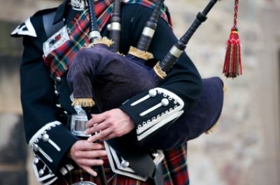 image of the midsection of a piper holding a set of bagpipes