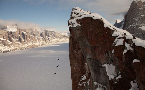 image of three tiny figures in the air next to a giant mountainside