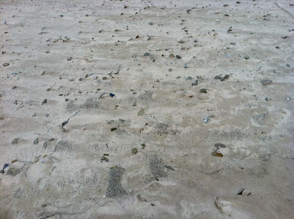 image of stones made smooth by the lake, buried in the sand