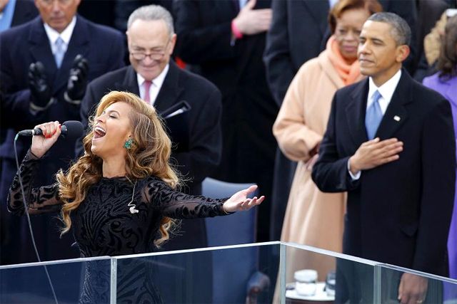 image of Beyoncé singing the National Anthem at the inaugural while President Obama is seen in the background with his hand over his heart