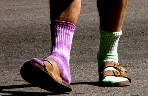 image of a man's lower legs; he is wearing mismatched socks and Birkenstock sandals