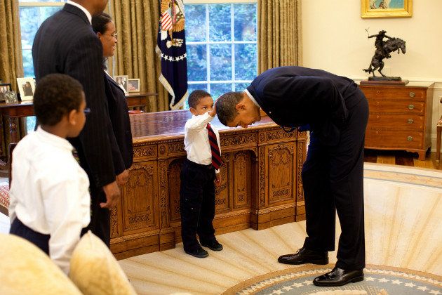 iconic image of the President leaning over in the Oval Office so a little black boy can touch his hair