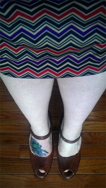 image of my lower half; I am wearing a purple, red, gold, and black chevron skirt and brown, heeled, open-toe Mary Janes