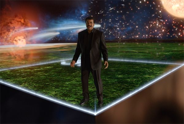 image of astrophysicist Neil deGrasse Tyson standing on the 'cosmic calendar' graphic from an episode of Cosmos