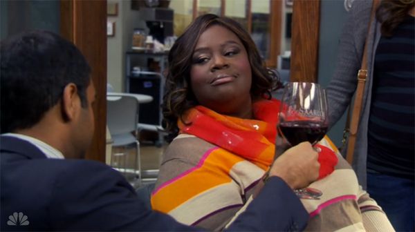 screen cap of Retta, a fat black middle-aged woman, clicking a glass of wine with Aziz Ansari, a young thin Indian American man
