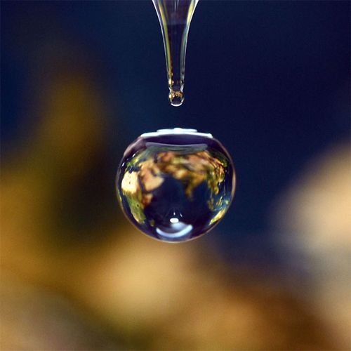 a drop of water through which can be seen a map of the earth
