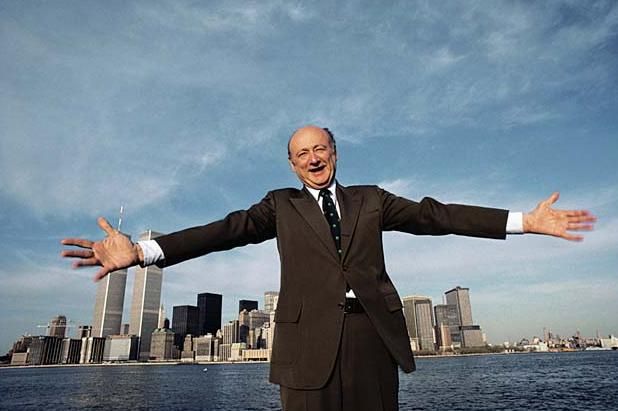 image of former NYC Mayor Ed Koch, standing in front of the NYC skyline with his arms spread, smiling
