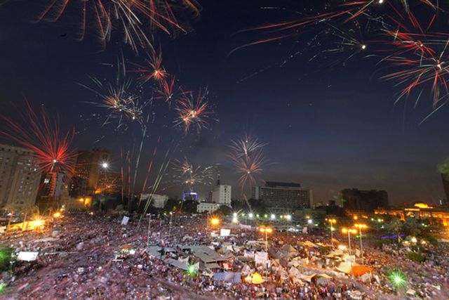 image of fireworks lighting up the night sky over Tahrir Square, filled with protestors