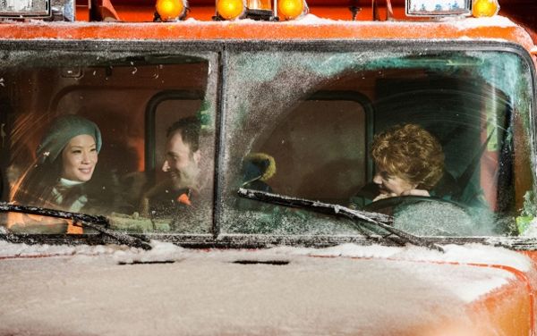 Joan Watson (Lucy Liu), Sherlock Holmes (Jonny Lee Miller), and Pam (Becky Ann Baker) sit, smiling, in the cab of a snowplow during a storm
