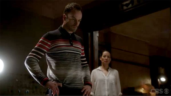 Jonny Lee Miller as Sherlock Holmes scowls at an evidence board while Lucy Liu as Joan Watson looks on