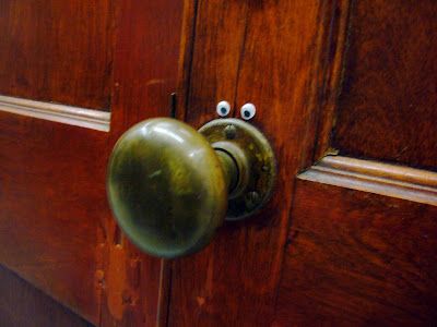 image of a wooden door with googly eyes stuck on just above the doorknob