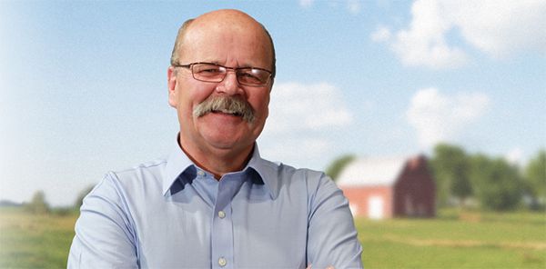 image of John Gregg, a smiling middle-aged white man with a thick mustache and glasses